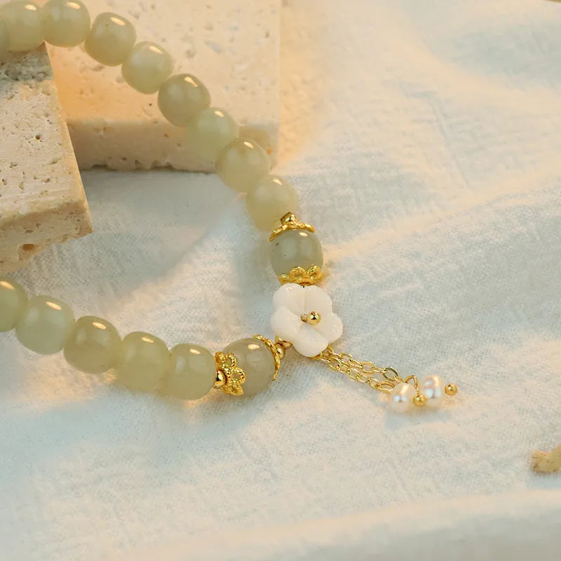 Close-up of sage-green beads, floral centrepiece and decorative gold-tone accents