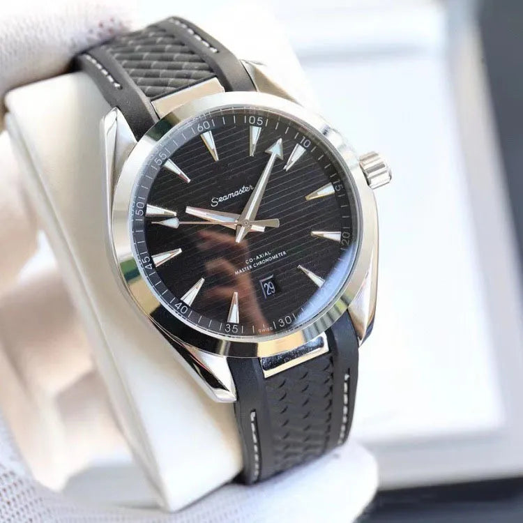 A close-up of a SeikoMaker men's watch with a black dial, silver-tone stainless steel case, and a black textured rubber strap, resting on a white display stand.