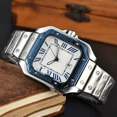 A men's stainless steel watch with a square silver-tone case, blue bezel accents, a white dial with blue Roman numerals, and a matching metal link bracelet, styled on a wooden surface.
