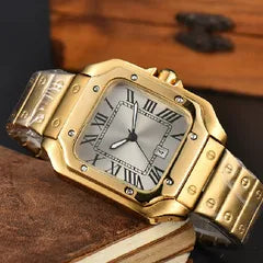 A gold-tone stainless steel watch with an octagonal bezel, silver dial, and matching gold-tone link bracelet, resting on a brown leather surface.