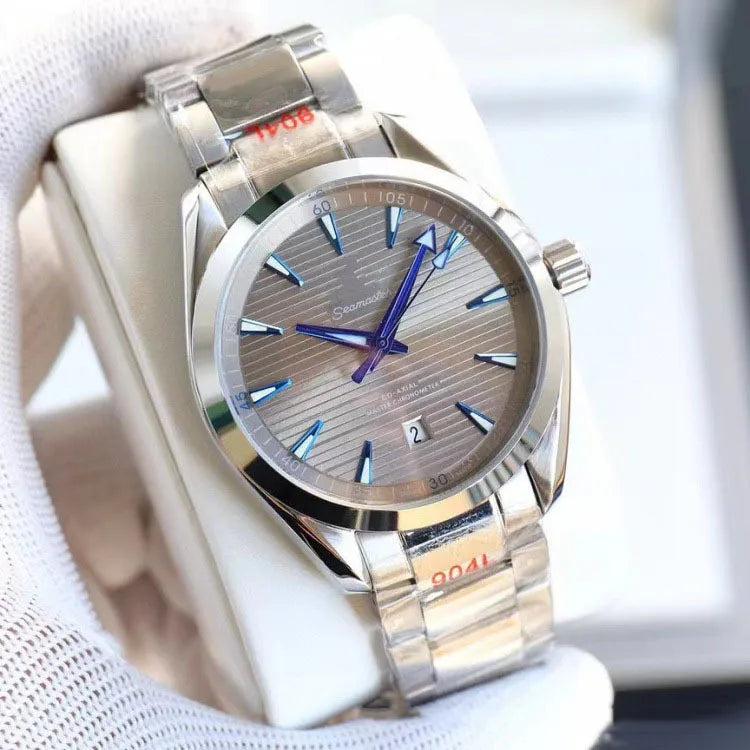 A stainless steel wristwatch with a silver dial and matching steel bracelet, held in a white glove. The watch features blue hands and blue hour markers on a silver-toned bezel.