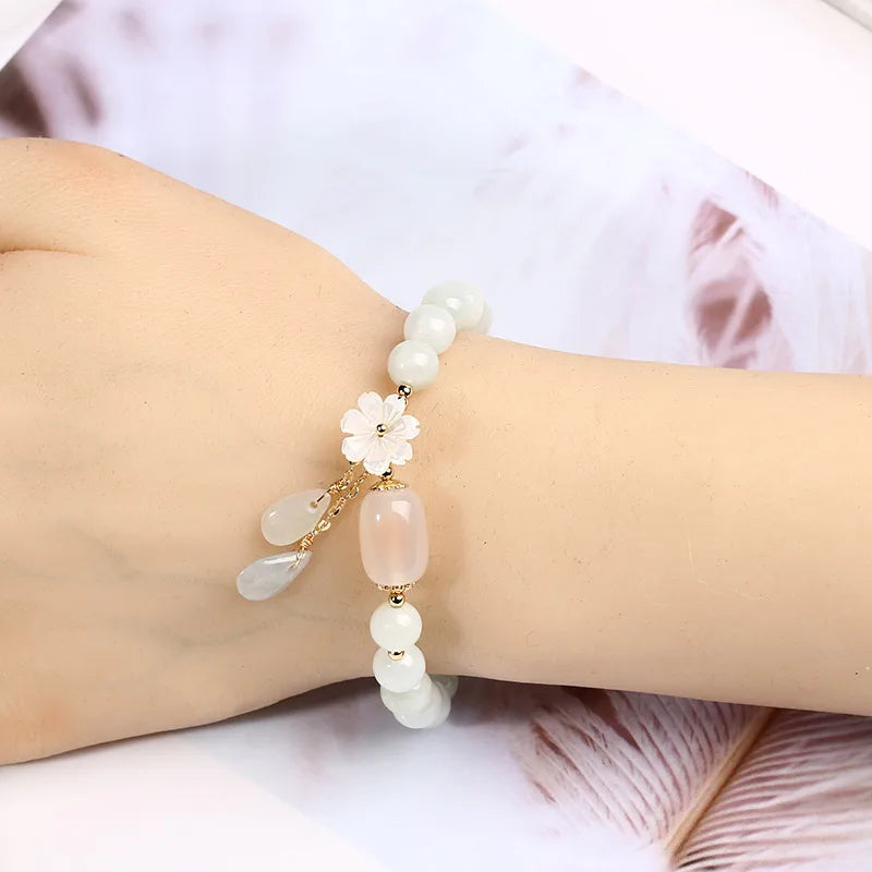 Close-up of floral detail and teardrop charms on pale beaded bracelet