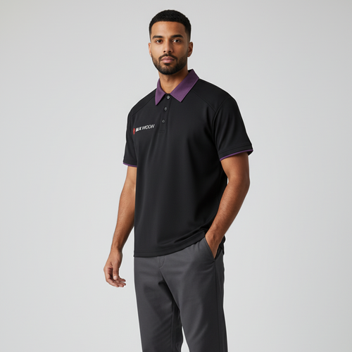 A man modeling a black short-sleeve polo shirt with a purple collar and sleeve trim, paired with dark gray trousers and black sneakers, against a light gray studio background.