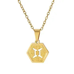 A gold hexagonal pendant necklace featuring a white Gemini zodiac symbol in the center, suspended from a gold chain against a plain white background.