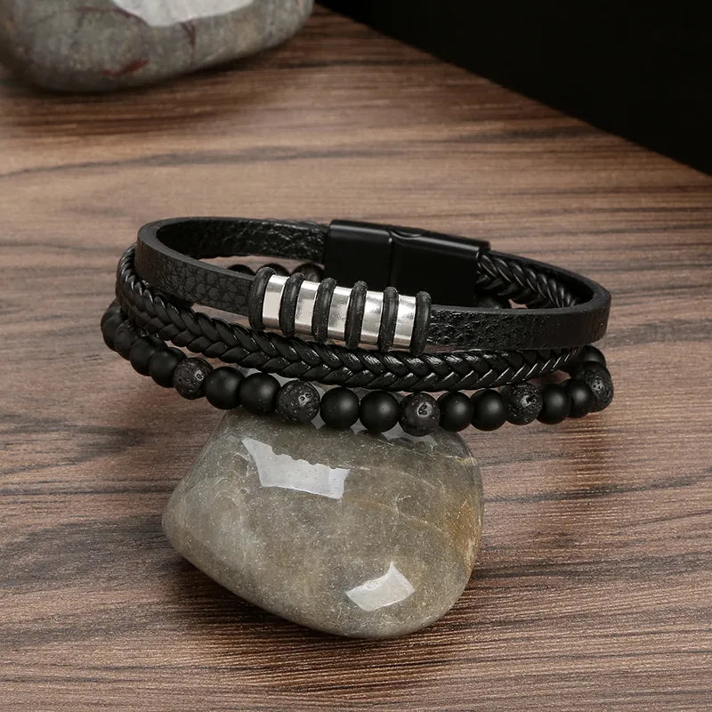Black layered bracelet with dark beads and silver-tone accents on a stone
