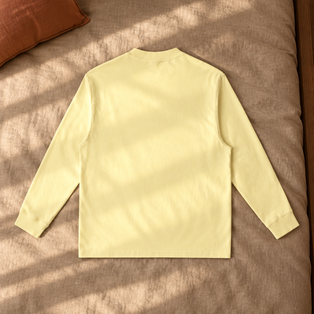 Plain butter-yellow long-sleeve T-shirt back on sunlit bedding