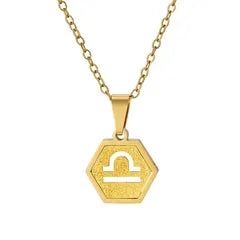 A gold hexagonal pendant necklace featuring the Libra zodiac symbol, suspended from a gold link chain against a plain white background.